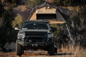 A truck is parked by the roadside with a setup rooftop tent.